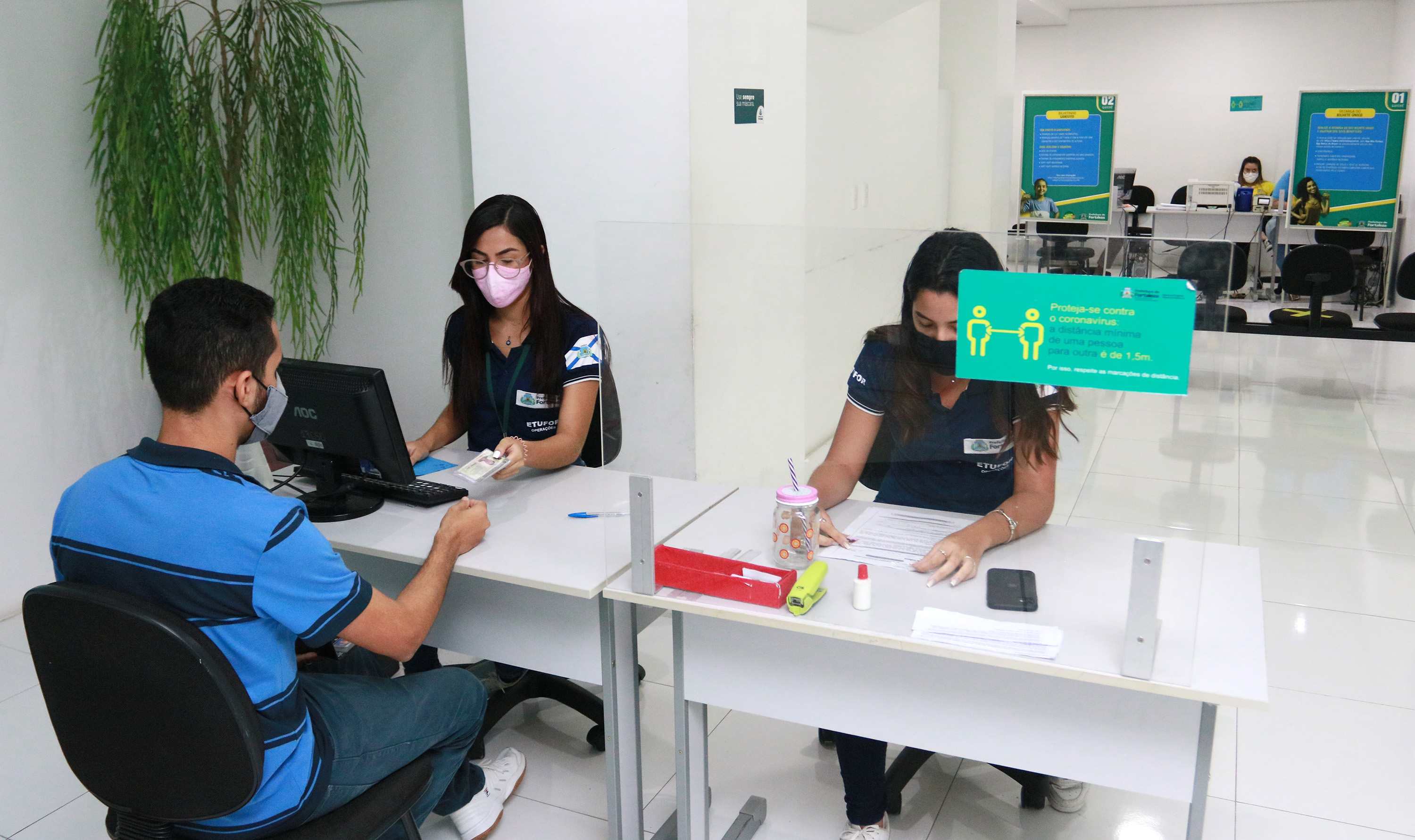 um jovem de costas é atendido em um guichê na central de atendimento da Etufor